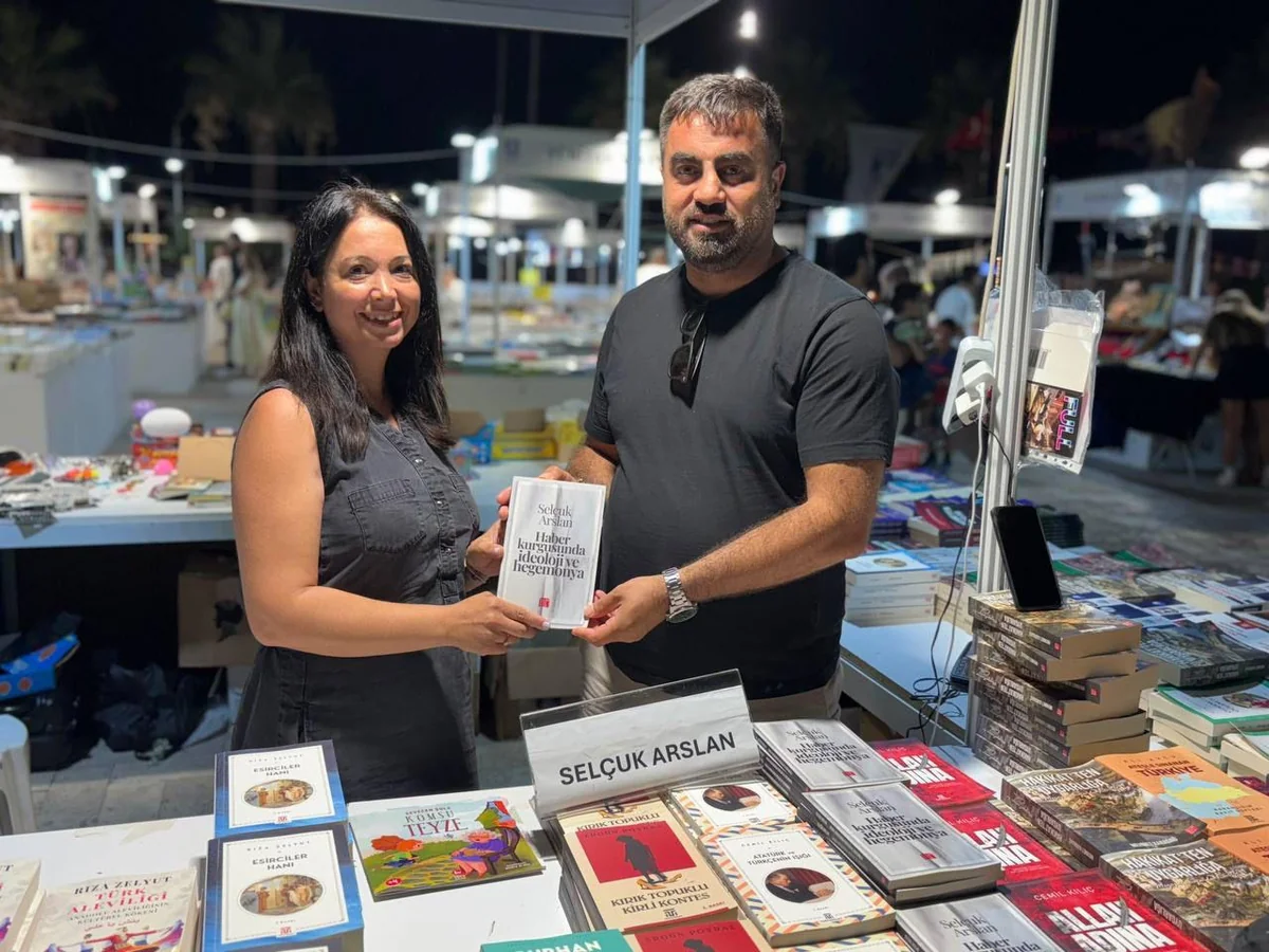 Bodrum Kitap ve Edebiyat Fuarı’nda (2026) kitaplarının başında duran bir yazar.